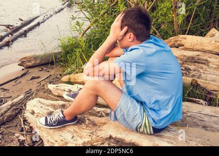 Tone Photo of Sad Young Man Sit on the Log all'aperto Foto Stock