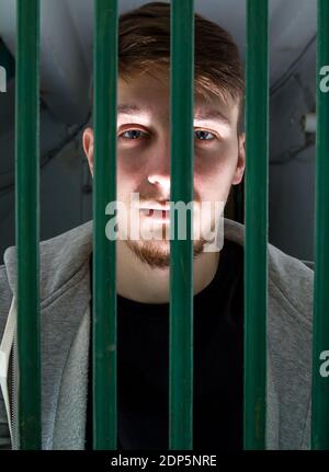 Jailed Young Man dietro le sbarre in una cella Foto Stock