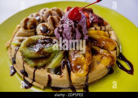 Gelato, frutta e sciroppo di cioccolato sopra un waffle Foto Stock