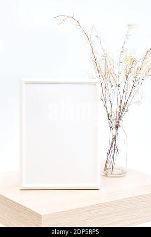 Simulato su di una cornice fotografica bianca in un minimalista interno con un bouquet di pampas erba in un bicchiere vase contro uno sfondo bianco della parete Foto Stock