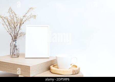 Simulato su di una cornice fotografica bianca in un minimalista interno con un bouquet di pampas erba in un bicchiere vase contro uno sfondo bianco della parete Foto Stock