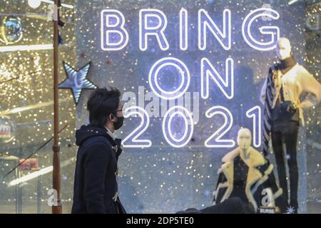 Un acquirente della mattina presto passa davanti a un cartello che dice ‘Bring Il 2021’ nel centro di Leeds come secondo paese le restrizioni di blocco nazionali terminano e cadono al livello 3 in Yorkshire occidentale Foto Stock