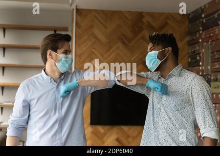 Sorridendo uomini diversi in maschere saluto toccando gomiti Foto Stock