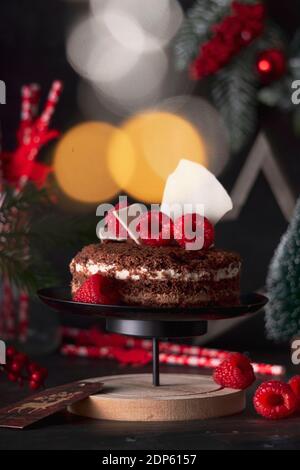 sponge cake three chocolates in a New Year's holiday decoration with raspberries. on dark background Stock Photo