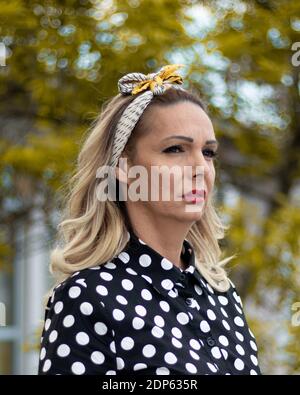 Un ritratto di una donna di mezza età con capelli biondi, fairband, e rossetto rosso nel parco, aspetto curioso Foto Stock