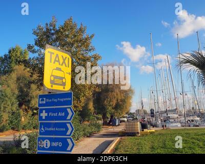 Varie indicazioni sulla strada in rosso, giallo, nero e blu presso un porto turistico in Grecia Foto Stock