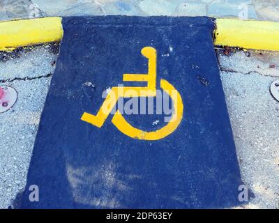Cartello giallo per disabili che indica uno spazio in un parcheggio, su sfondo blu in un porto turistico in Grecia Foto Stock