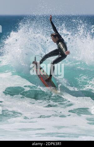 Azione spettacolare mentre un giovane surfista cavalca un'onda a Fistral a Newquay in Cornovaglia. Foto Stock