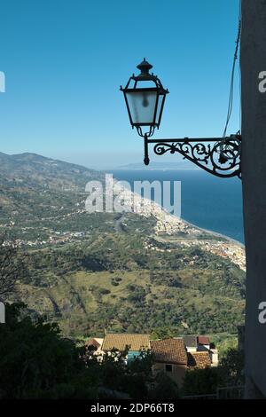 Alto punto di vista sulla costa orientale densamente popolata della Sicilia vicino al mare, nella sagoma in primo piano di un vecchio stile lanterna Foto Stock