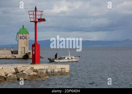 Barca da pesca che parte attraverso l'ingresso del porto di Bol, isola di Brac, Dalmazia, Croazia, Europa. Foto Stock