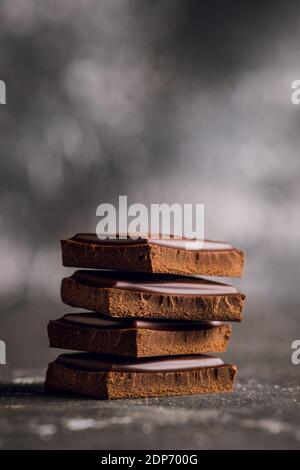 Pezzi di barrette di cioccolato su sfondo nero rustico. Messa a fuoco selettiva. Profondità di campo poco profonda. Foto Stock