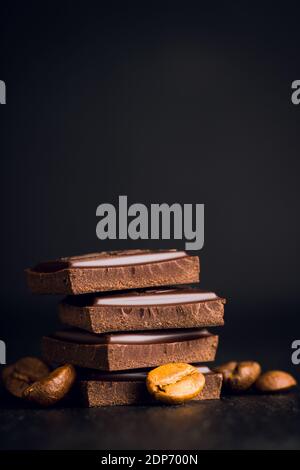 Pezzi di barrette di cioccolato su sfondo nero rustico. Messa a fuoco selettiva. Profondità di campo poco profonda. Foto Stock