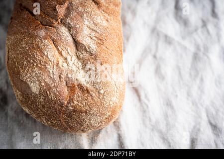 Pane appena sfornato sul vecchio tavolo di legno. Messa a fuoco selettiva. Profondità di campo poco profonda. Foto Stock