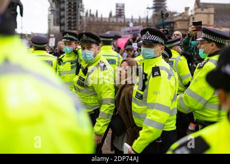 Una donna di arresto è guidata via dalla polizia durante la protesta contro il vaccino COVID-19, Parliament Square, Londra, 14 dicembre 2020 Foto Stock