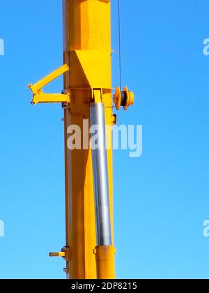 Dettaglio di un braccio giallo per gru a sollevamento pesante con una brillante cielo blu sullo sfondo Foto Stock
