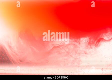Inchiostro colorato su sfondo bianco.goccia arancione giallo che rotea sotto l'acqua. Nube di vernice acrilica in acqua. Foto Stock