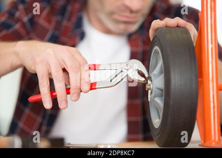 immagine ritagliata dell'operatore che fissa una ruota del carrello con una pinza Foto Stock