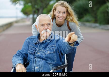 uomo anziano e giovane donna in sedia a rotelle Foto Stock