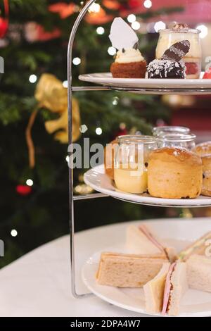 Tè pomeridiano festivo con panini, focaccine e budini. Natale albero bokeh luce sullo sfondo. Inverno e umore. Messa a fuoco selettiva. Foto Stock