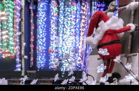 Babbo Natale sale le scale di legno fino al camino della casa sullo sfondo di coloratissimi ghirlande. Foto Stock