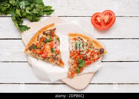 Primo piano, due pezzi di pizza calda con formaggio su sfondo di legno bianco. Foto Stock