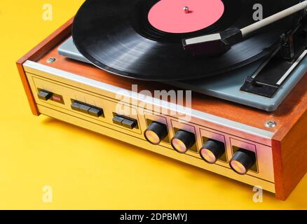 Frammento di un lettore di dischi in vinile con un piatto su sfondo giallo. Cultura retrò Foto Stock