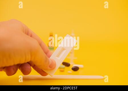 Mano maschio che mostra il test dell'antigene con risultato negativo su sfondo giallo. Foto Stock