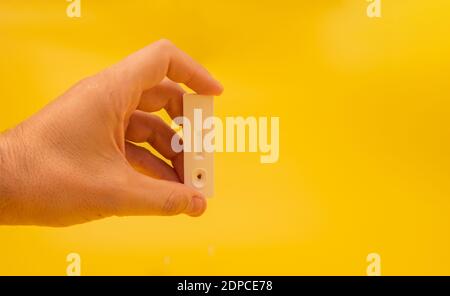 Mano maschio che mostra il test dell'antigene con risultato negativo su sfondo giallo. Foto Stock