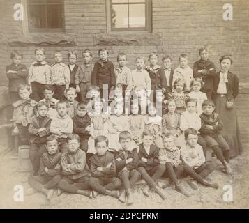 Antique 1902 Fotografia, gruppo scolastico della Charles Street School con l'insegnante Miss Dennon, a New York City, New York. FONTE: FOTOGRAFIA ORIGINALE Foto Stock