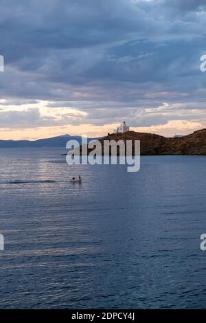 Grecia, isola di Kea Tzia. Faro bianco su un promontorio roccioso, cielo blu nuvoloso e barca a vela in mare ondulato scintillante sfondo d'acqua. Estate, pomeriggio Foto Stock