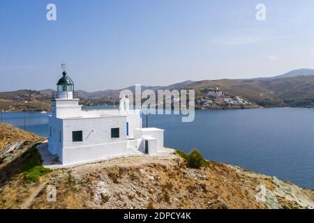 Grecia, isola di Kea Tzia. Veduta aerea del drone del faro e della chiesa bianca di San Nicola su un promontorio roccioso, cielo blu chiaro e acqua di mare ondulata trasparente Foto Stock