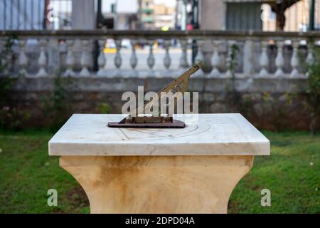 Metallo vecchia meridiana al Giardino Nazionale di Atene, destinazione Grecia. Antico orologio astronomico con gnomone in acciaio arrugginito su marmo a botanica Foto Stock