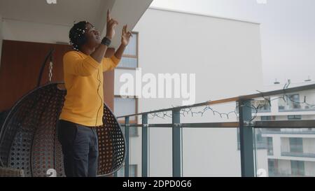Divertente uomo nero afroamericano con le cuffie che ballano sulla terrazza. Foto di alta qualità Foto Stock
