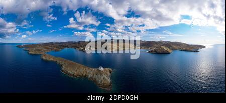 Grecia, isola di Kea Tzia. Drone, vista panoramica aerea del faro e la chiesa di Agios Nikolaos su un promontorio roccioso, cielo blu chiaro e trasparente increspato Foto Stock