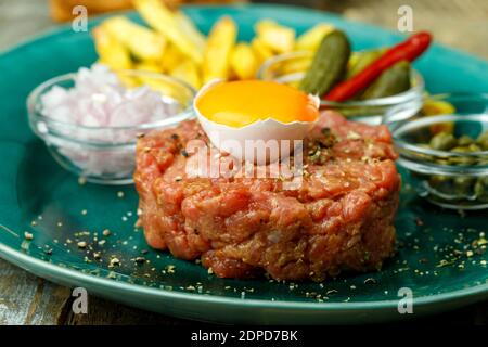 tartare di bistecca con uovo aperto su legno Foto Stock