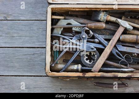 Vecchia valigia con i diversi attrezzi manuali sulle tavole di legno Foto Stock