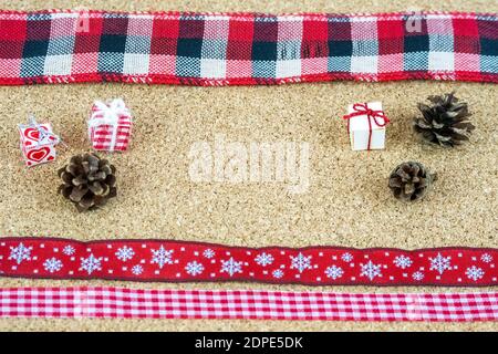 Elementi decorativi di Natale organizzati su teli di legno di corkwood. Minuscoli scatole di carta, nastri e piccoli coni di pino. Foto Stock