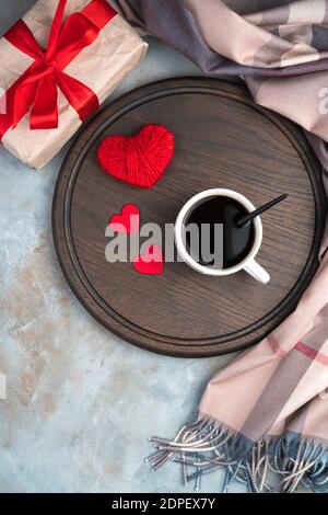 Sfondo romantico con tazza di caffè, cuori e regalo su sfondo grigio. Foto Stock