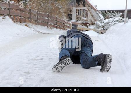 Pericolo di incidenti in inverno. Un uomo scivola fuori sulla strada liscia Foto Stock