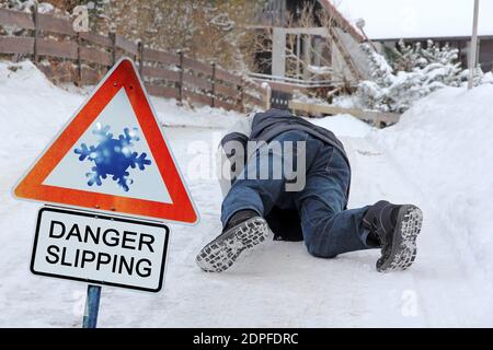 Pericolo di incidenti in inverno. Un uomo scivola fuori sulla strada liscia Foto Stock