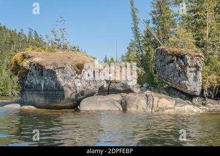 Tre enormi massi di granito con sommità in muschio si trovano in prossimità di una costa rocciosa in una remota area selvaggia della costa della British Columbia. Foto Stock