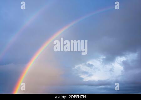 Arcobaleno reale in un paesaggio nuvoloso con un buco nel nuvole Foto Stock