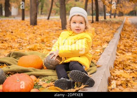 Bambina carina con zucche nel parco autunnale Foto Stock