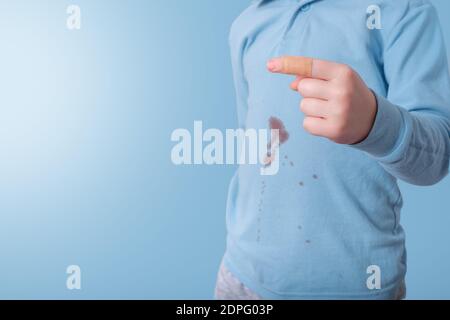 Closeup del dito del bambino con sticking-gesso. Sporco sangue macchia sulla t-shirt sullo sfondo. Luogo per il testo Foto Stock