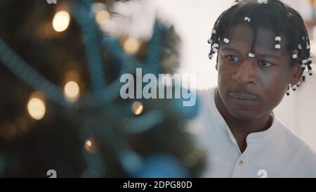 Giovane uomo nero afroamericano che decora l'albero di natale, primo piano. Foto di alta qualità Foto Stock