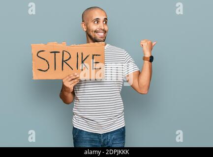 Uomo ispanico adulto che tiene il cartone di bandiera di colpo che punta il pollice in su al lato sorridente felice con bocca aperta Foto Stock