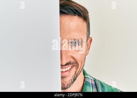 Bell'uomo con barba che tiene in bianco banner vuoto che copre metà faccia sorridente con un sorriso felice e fresco sul viso. Mostrando i denti. Foto Stock