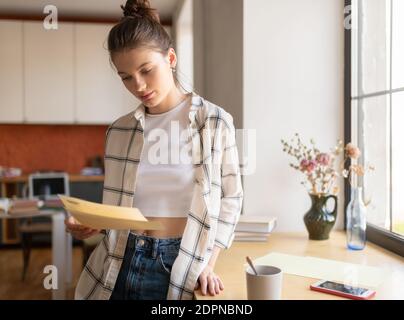 Bella studentessa teenage focalizzata studentessa membfully studiando le note che si preparano per esame a casa Foto Stock