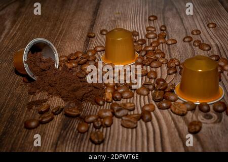 Aprire la capsula del caffè espresso con il caffè macinato all'interno. Cialde di caffè e chicchi di caffè arrostiti su sfondo di legno. Foto di alta qualità Foto Stock