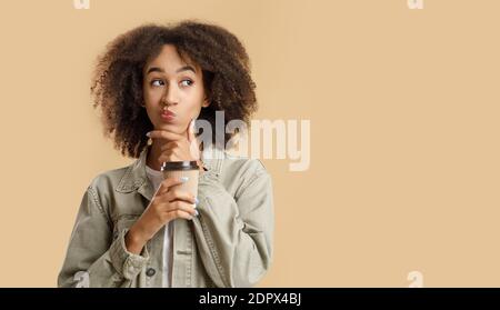 Offerta insolita, pensateci e scelta. Donna afroamericana pensiva, contiene una tazza di caffè Foto Stock